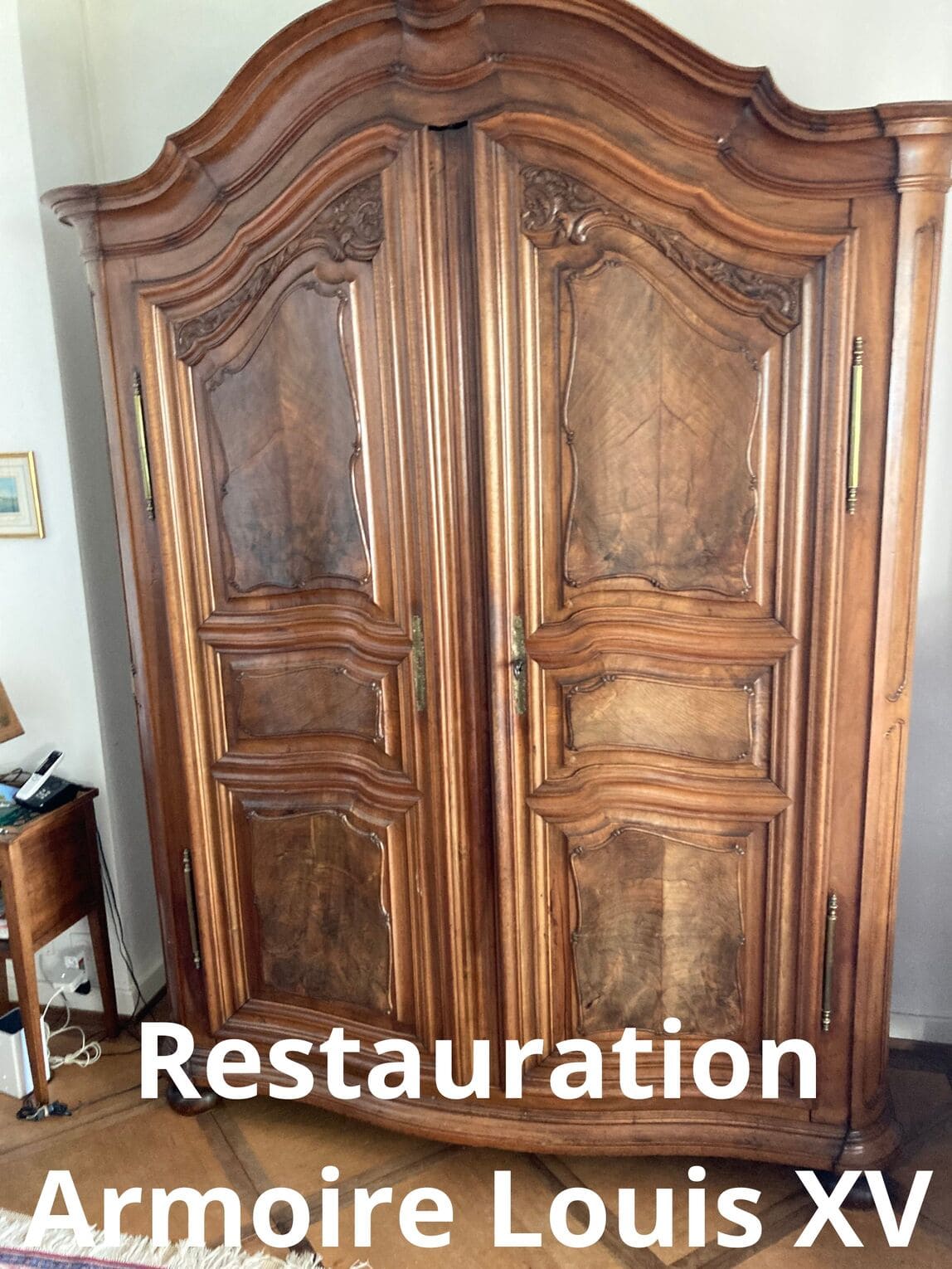 Wooden wardrobe after restoration showing a refined finish with renewed surface and reinforced base, displayed in workshop setting with natural lighting highlighting the craftsmanship details