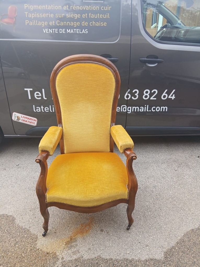Golden yellow upholstered armchair with wooden frame and curved armrests fully restored, displayed in natural outdoor light in front of professional work van, showing pristine fabric and quality craftsmanship