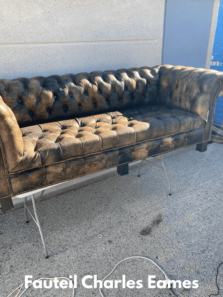Golden yellow upholstered armchair with wooden frame and curved armrests fully restored, displayed in natural outdoor light in front of professional work van, showing pristine fabric and quality craftsmanship